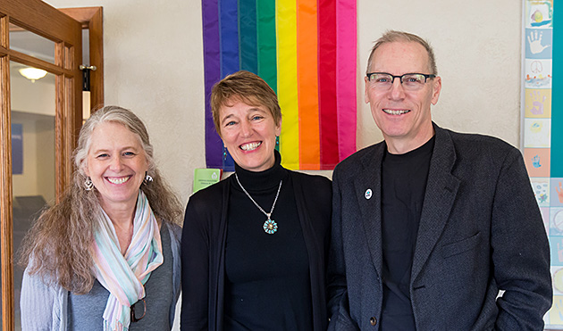 people standing before a pride flag